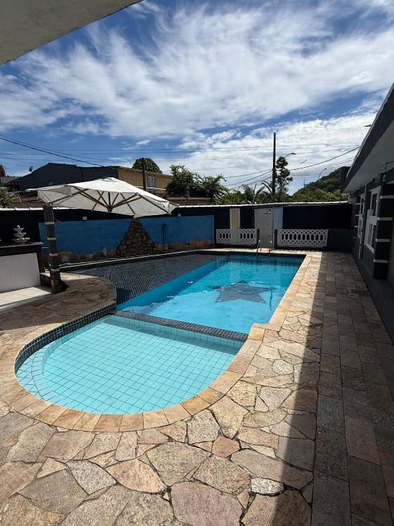 a swimming pool with blue water in a yard at Casa praia e piscina in Bertioga