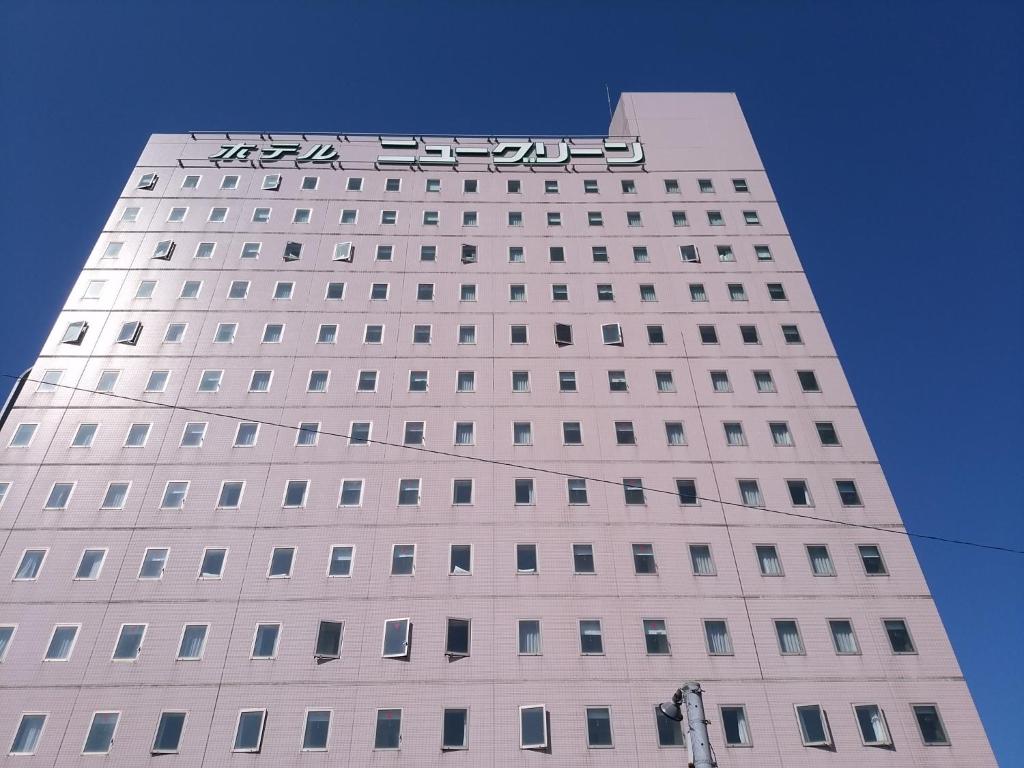 Hotel New Green Kashiwazaki في كاشيوازاكي: مبنى أبيض طويل عليه علامة