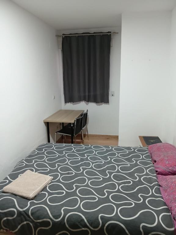 a bedroom with a bed and a desk and a window at EMMI Guesthouse in Alicante