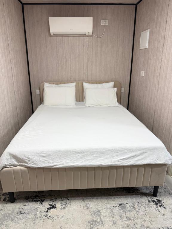 ein Bett in einem kleinen Zimmer mit weißen Laken und Kissen in der Unterkunft GoGolan in Madschdal Schams