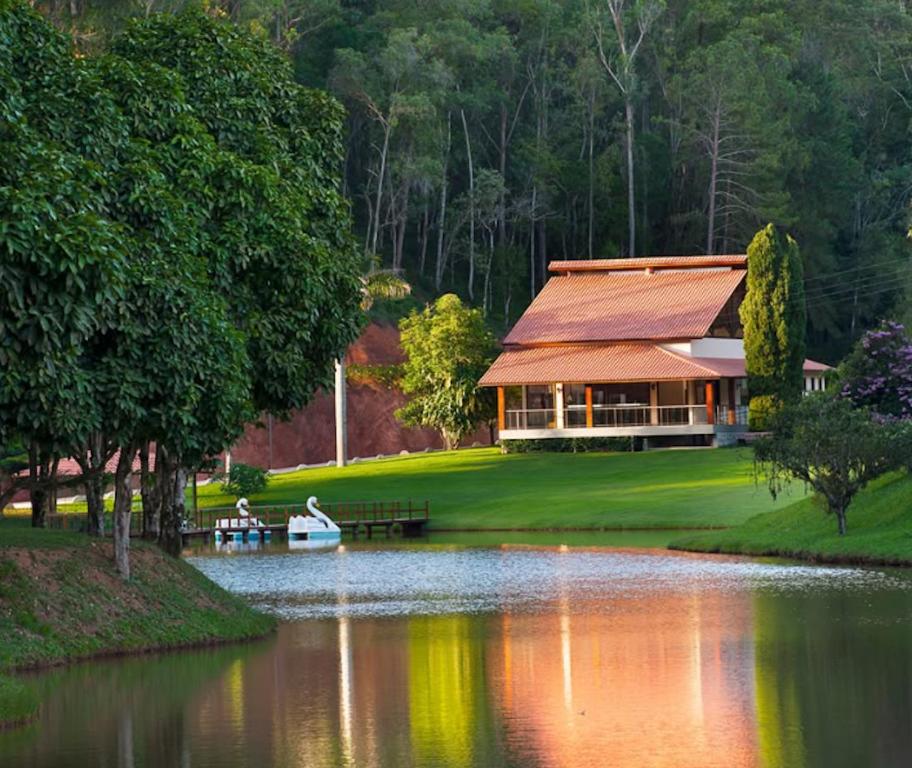 a house on a lake with a boat in front of it at Sítio dos Lagos in Domingos Martins