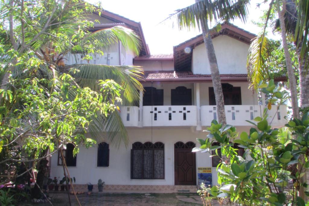 una casa blanca con palmeras delante en Rainbow Guest House, en Mirissa