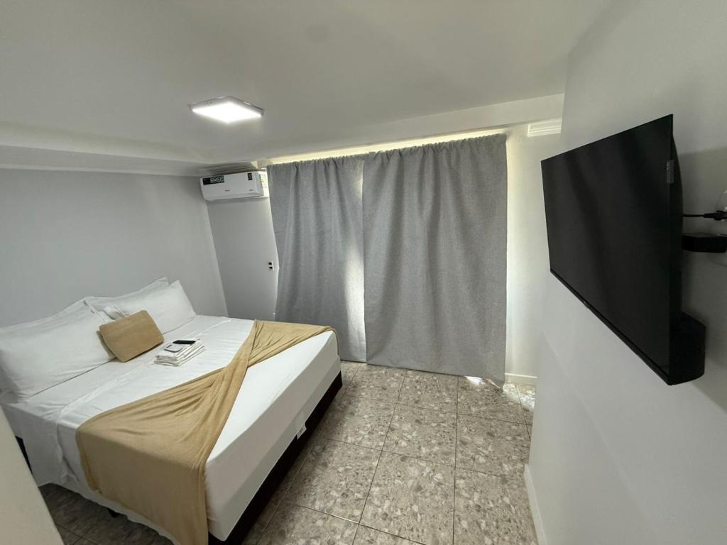 a bedroom with a bed and a flat screen tv at Downtown Rooftop 375 in Imbetiba