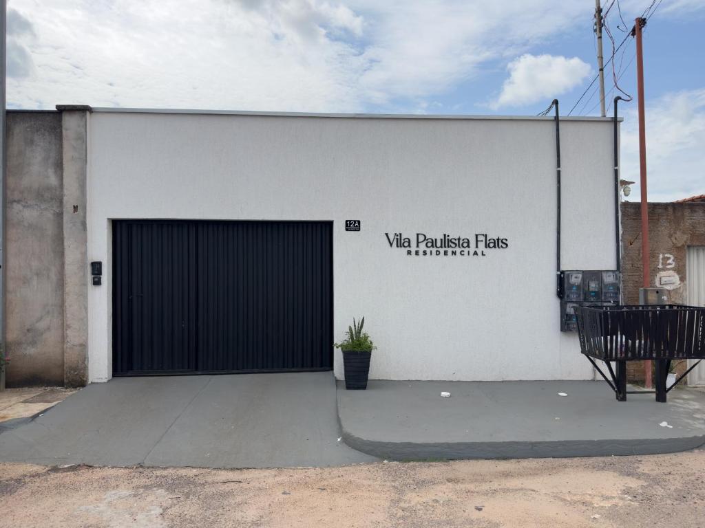 a white building with a black garage door and a bench at Flat Mobiliado no centro in Redenção