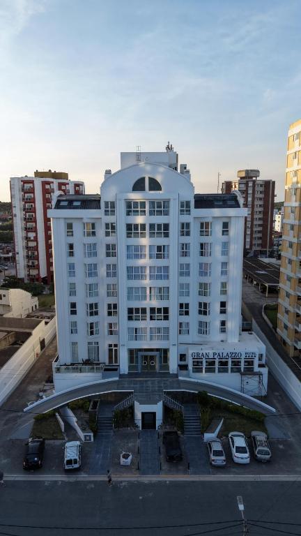 a large white building with cars parked in a parking lot at GRAN PALAZZO Hotel in Villa Gesell