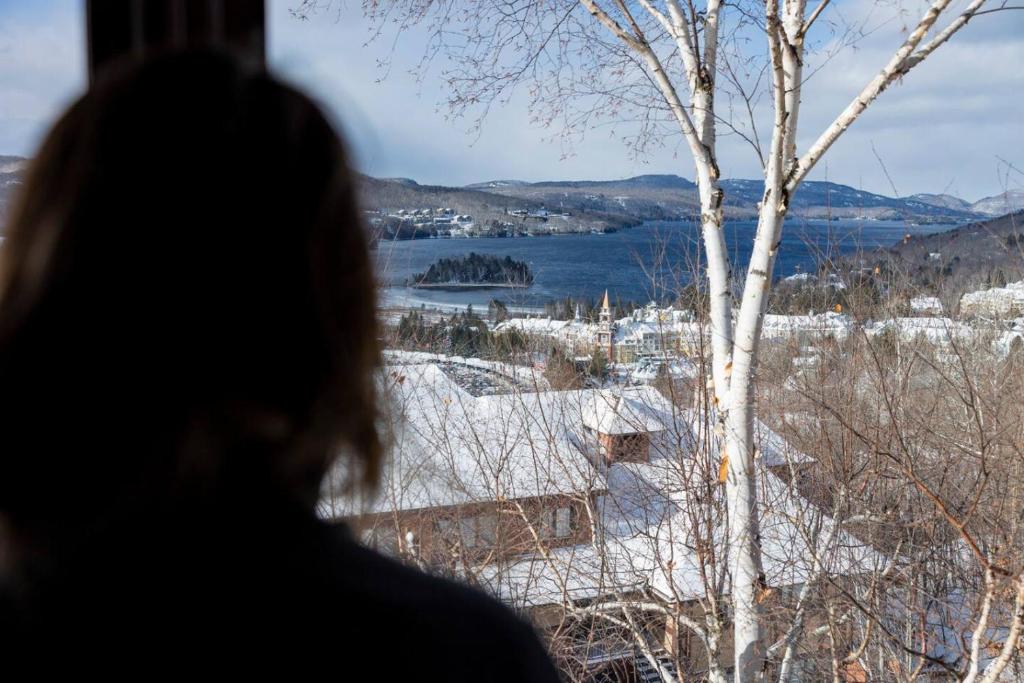 a woman looking out of a window at a snow covered town at Lake view - Ski In-Out in Mont-Tremblant