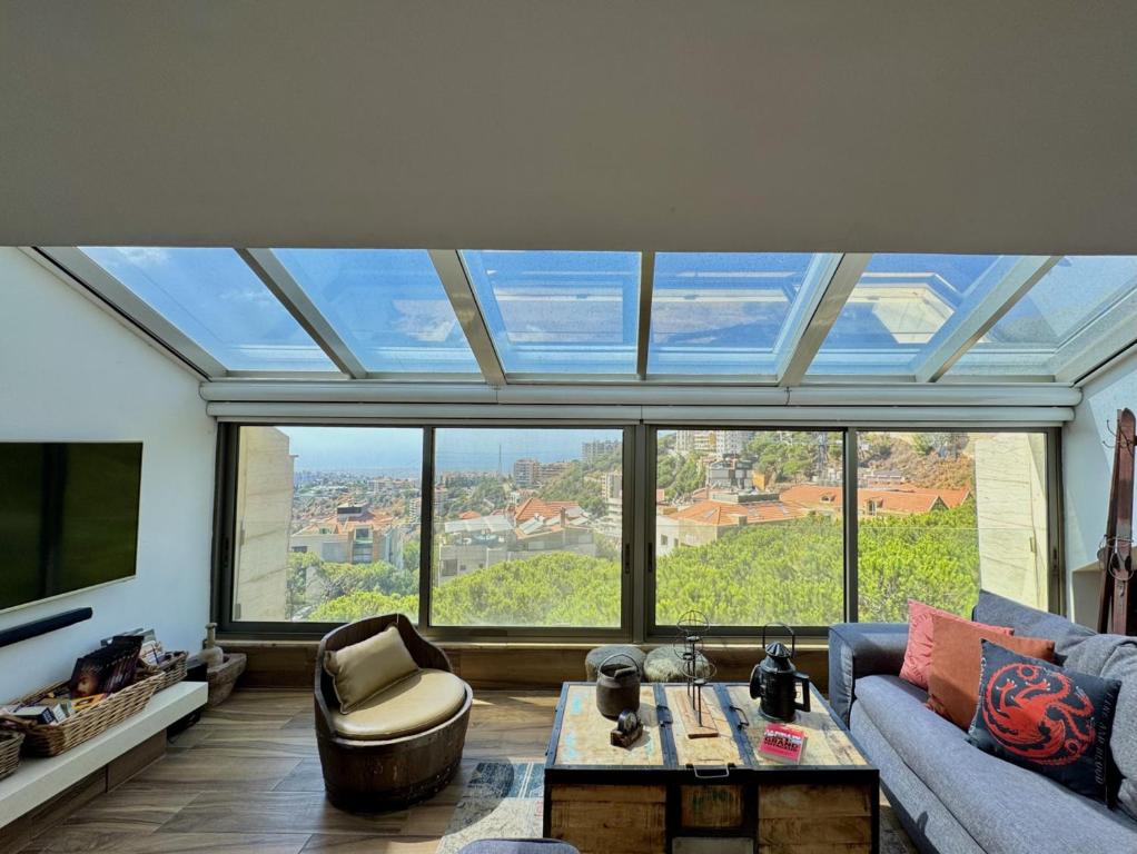 a living room with a large window and a couch at Deluxe Loft at Monteverde in Beit Meri