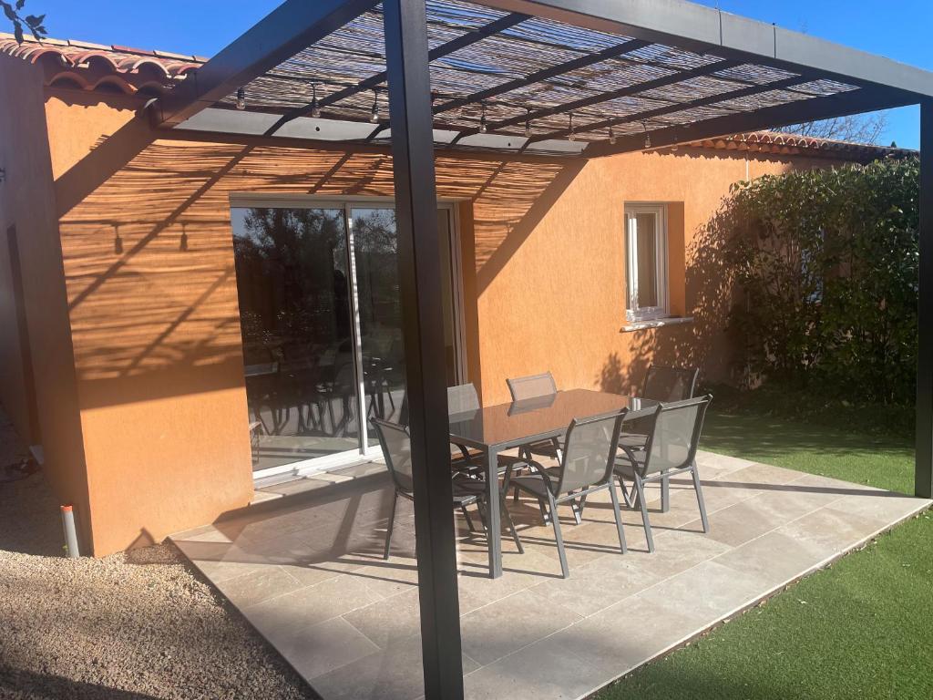 a patio with a table and chairs under a pergola at La Villa d Isa in La Motte