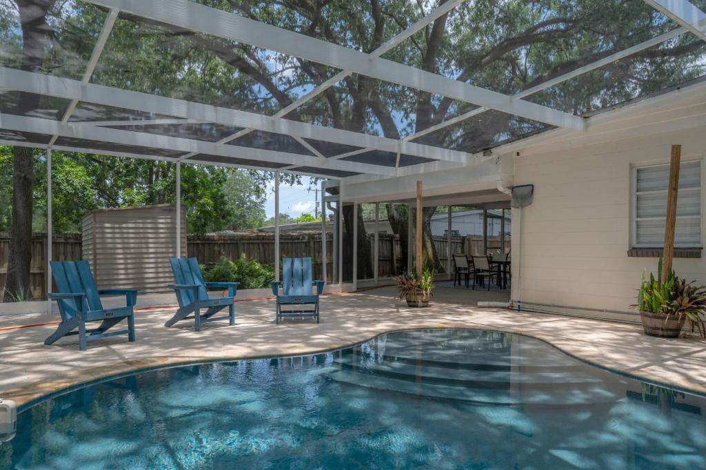 a patio with a swimming pool with chairs and a pergola at Spacious Boho Retreat Heated Pool-HotTub-Huge Yard in Tampa