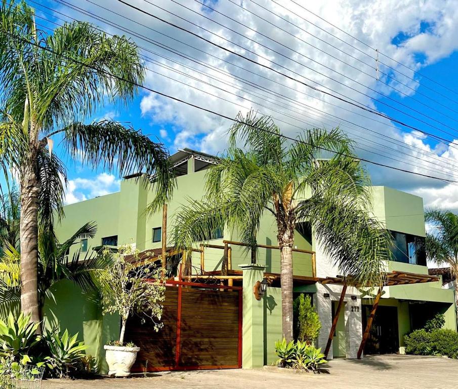 a green house with palm trees in front of it at Hotel Zona Sul in São Gabriel