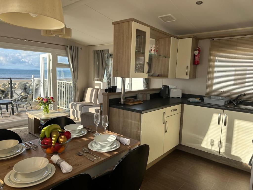 a kitchen and dining room with a table with a view of the ocean at Dolphin View in Llanddwywe