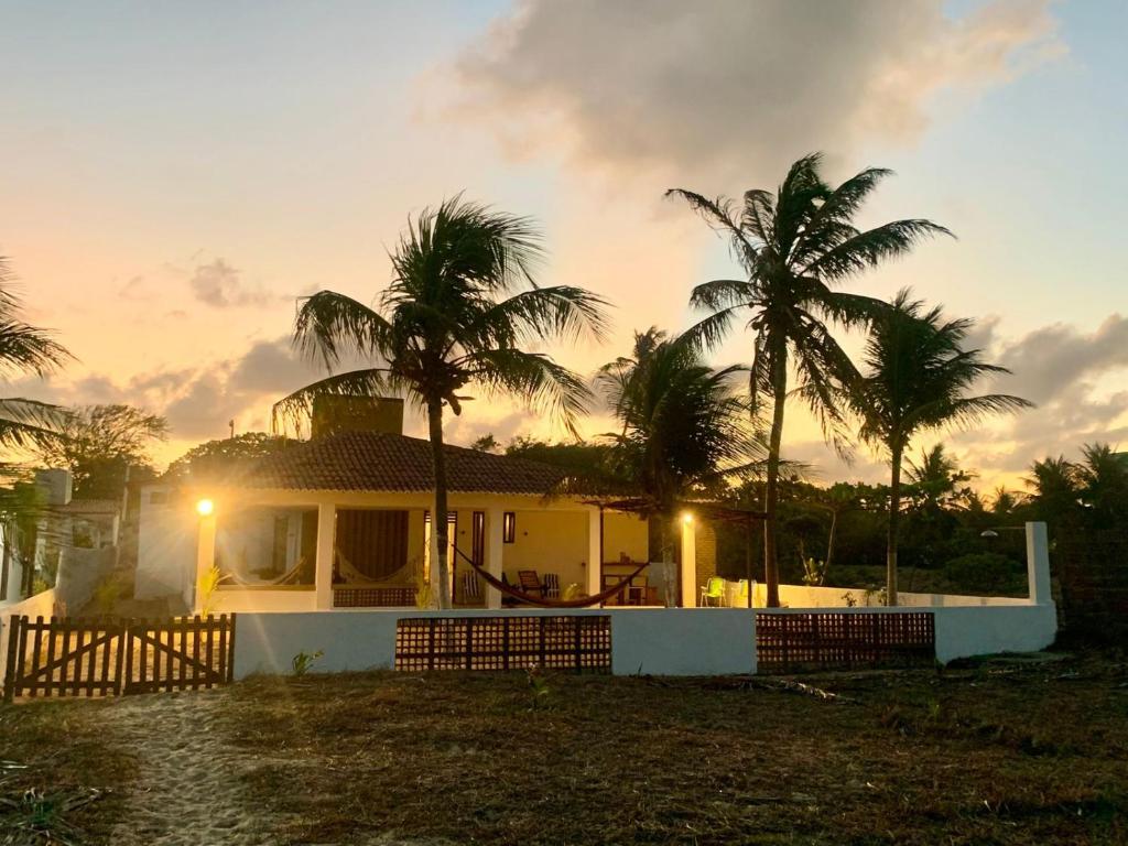 a house with palm trees in front of a sunset at Oca Teko Porã in Genipabu