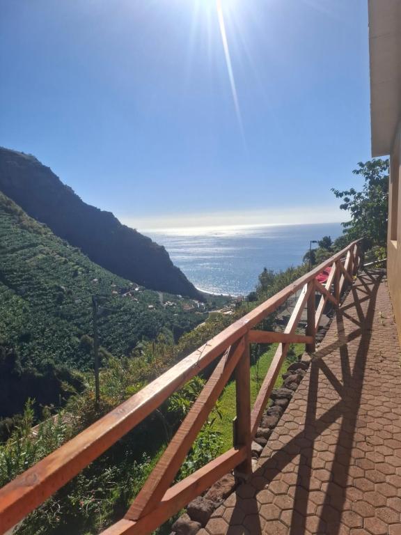 a wooden bridge with the ocean in the background at Levadinha - Nature guest house in Madalena do Mar