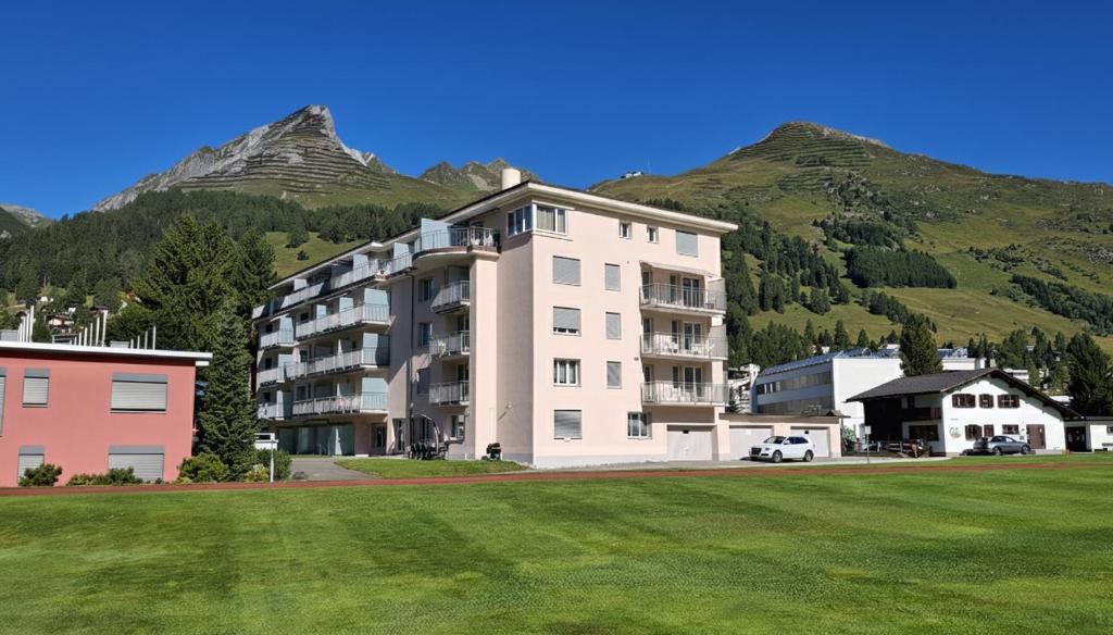 a large white building with a mountain in the background at Apartment Bünda in Davos
