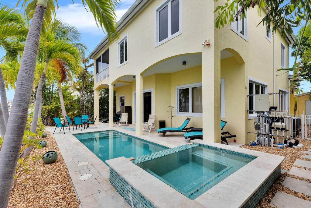 a swimming pool in front of a house with palm trees at Casa Mar in Islamorada