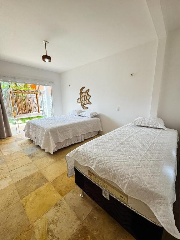 a bedroom with two beds and a large window at Pousada Vila Didi - Flats com Cozinha Completa in Barra Grande