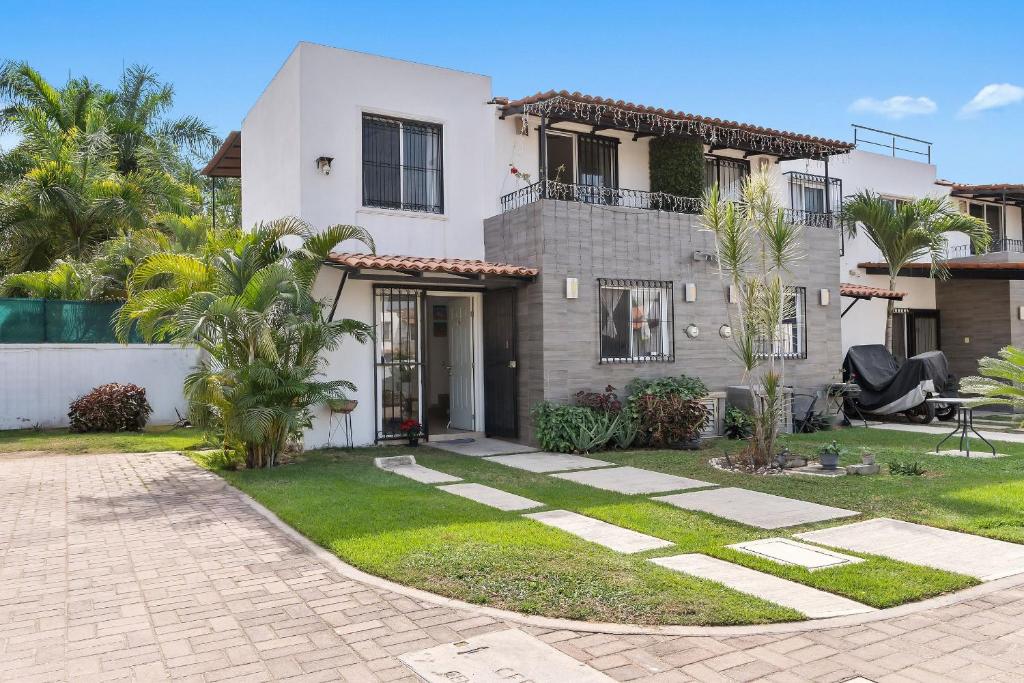 a white house with a yard with palm trees at Modern Pool Side, 3 Bdrm House with parking in Puerto Vallarta