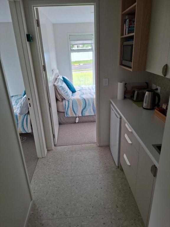 a room with a kitchen with a bed and a window at Time n Tide in Athenree