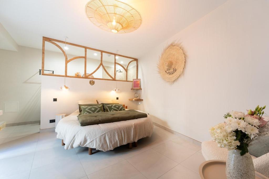 a bedroom with a bed and a vase with flowers at L'Escale - Une parenthèse en duo in Châteauneuf-du-Pape