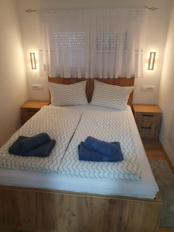 a bed with two blue pillows on it at Apartman Krznarić Centar in Županja