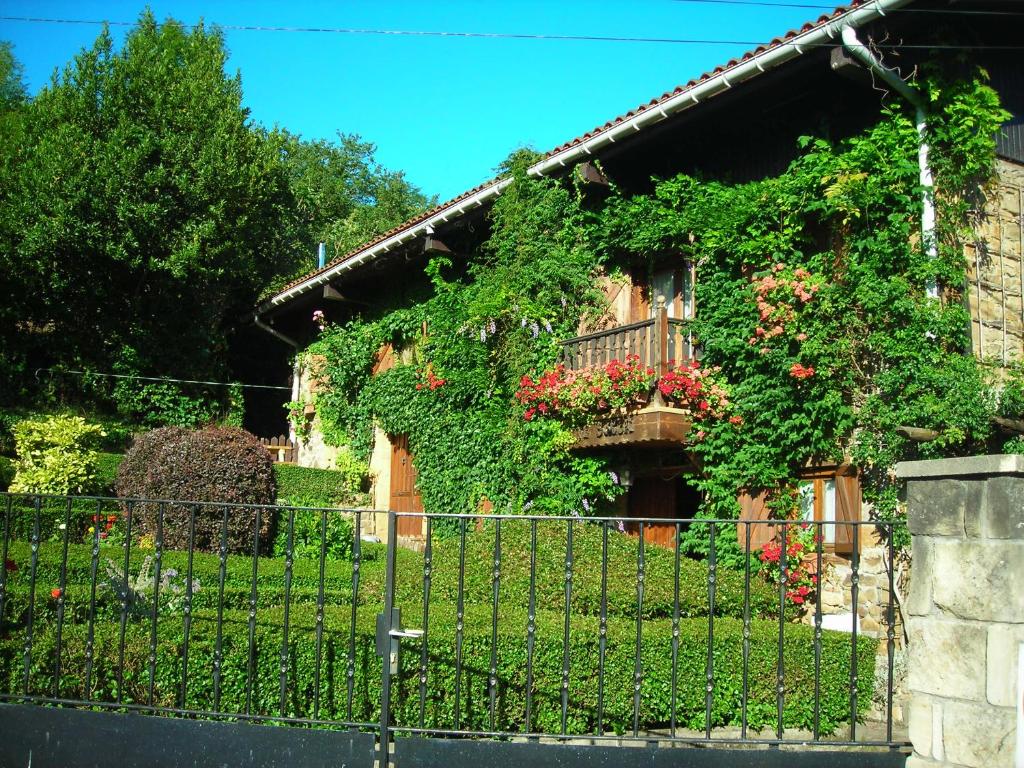 a house covered in ivy with a fence at Caserío Areitz Soroa in Arce