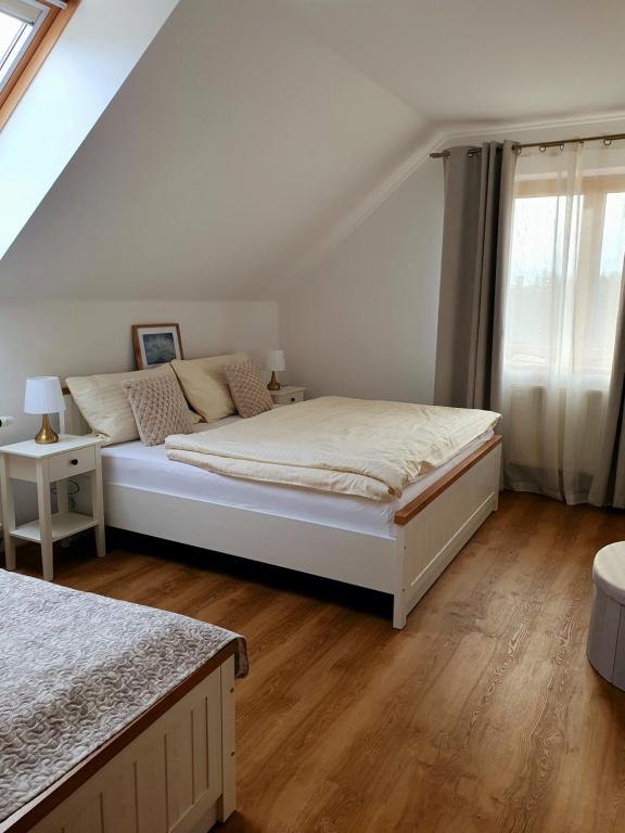 a white bedroom with a bed and a window at Penzion Apartmány Libošovice in Libošovice
