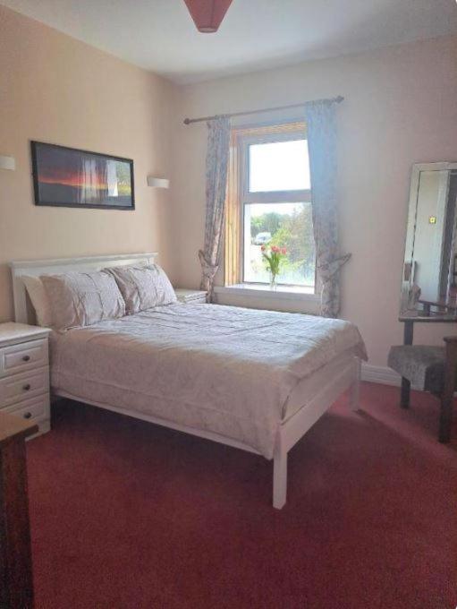 a bedroom with a large bed and a window at Teach Hudi Beag, Bar & Accommodation Bunbeg in Bunbeg