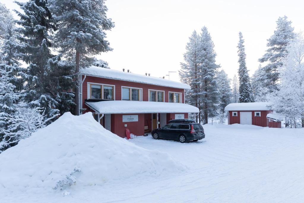 a car parked in front of a red house in the snow at Pyhäkoti B - 30 Meters From the Slopes - Valkea Homes in Pyhätunturi