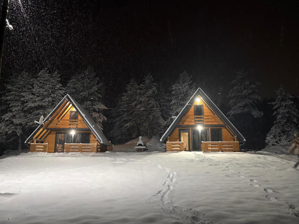 a log cabin in the snow at night at ROMANIJA vikendice in Koprivice