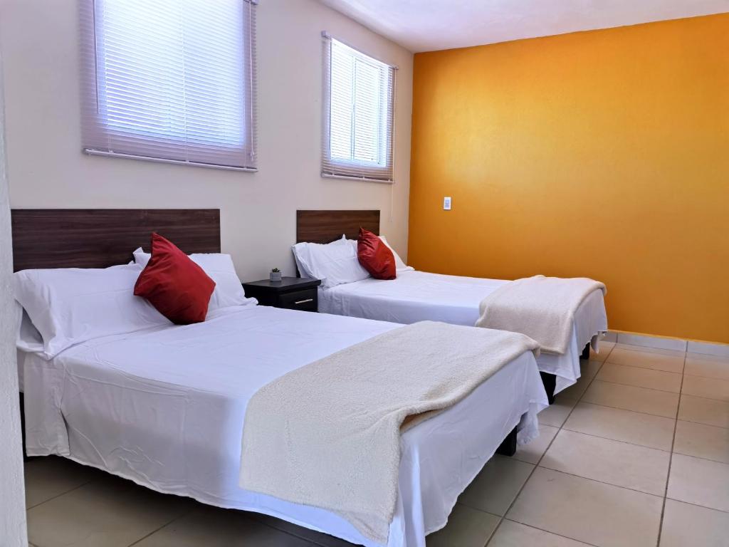 a bedroom with two beds with white and red pillows at Villa Platino Doble in Pachuca de Soto