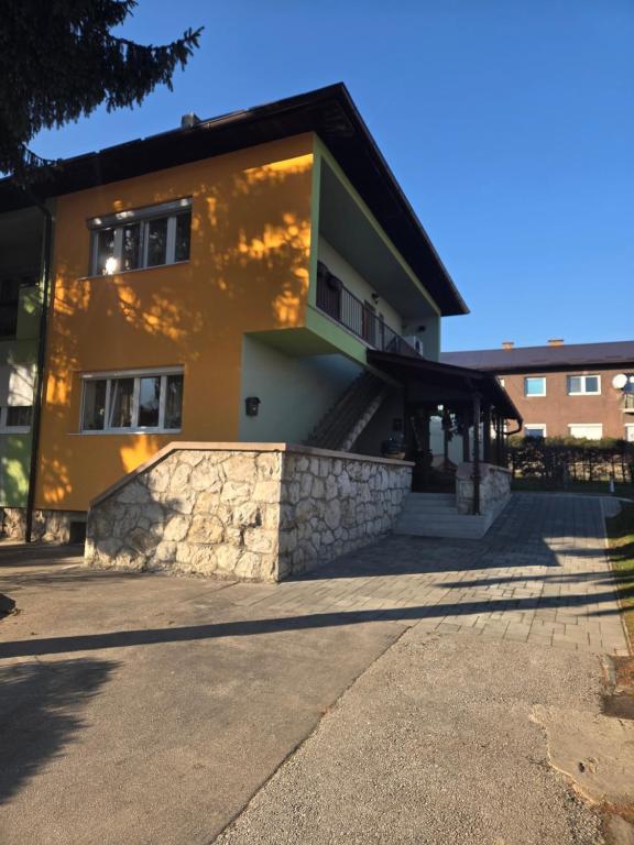 a house with a stone retaining wall and a building at Apartment SOFI Novi Travnik in Novi Travnik