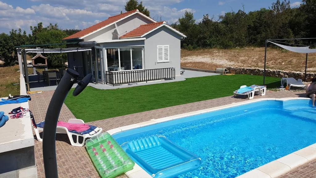 a swimming pool with two lawn chairs and a house at Nane Garden house with heated pool in Mirce