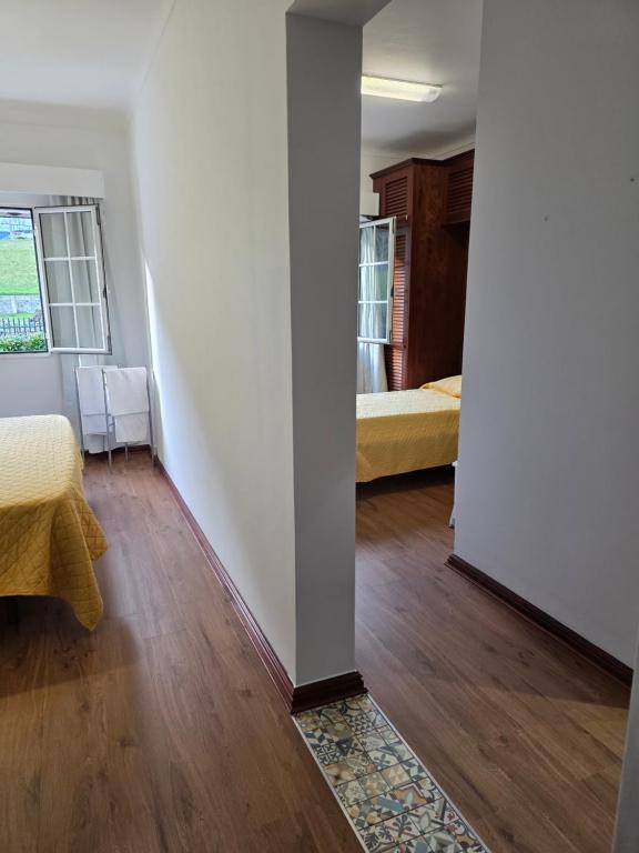 a room with white walls and wooden floors and two beds at Gorgeous House in Ponta Delgada