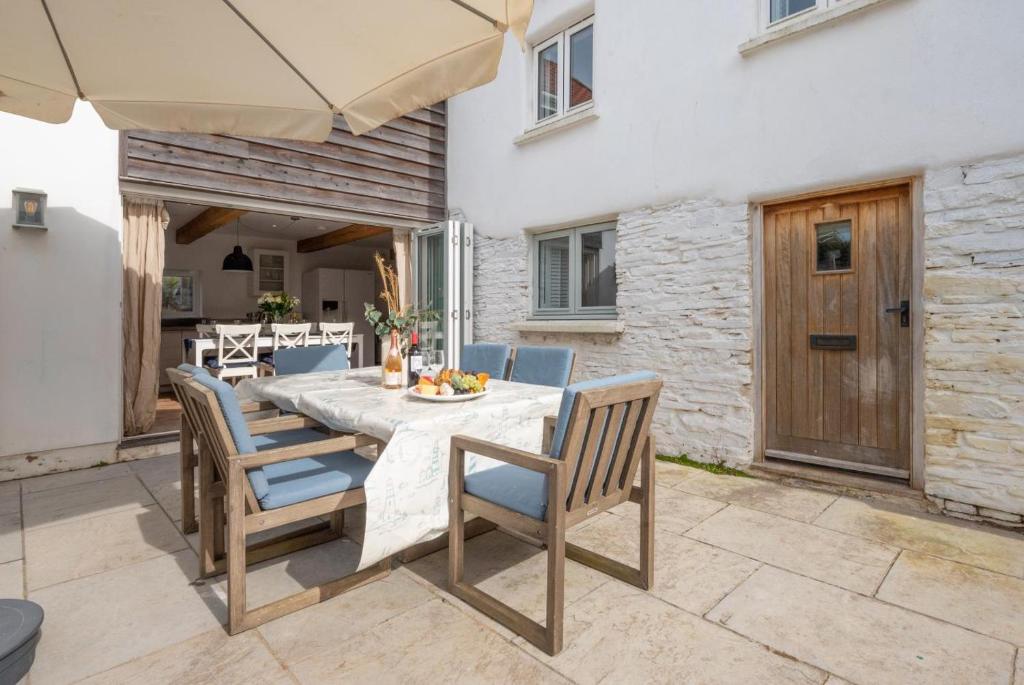 a table with chairs and an umbrella on a patio at 3 Bed in Croyde oc-croyco in Croyde