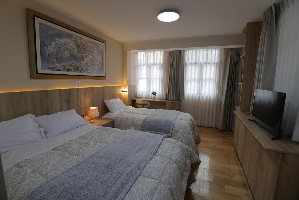 a hotel room with two beds and a flat screen tv at CASA ETEN Hospedaje Boutique - centro histórico de Cajamarca in Cajamarca