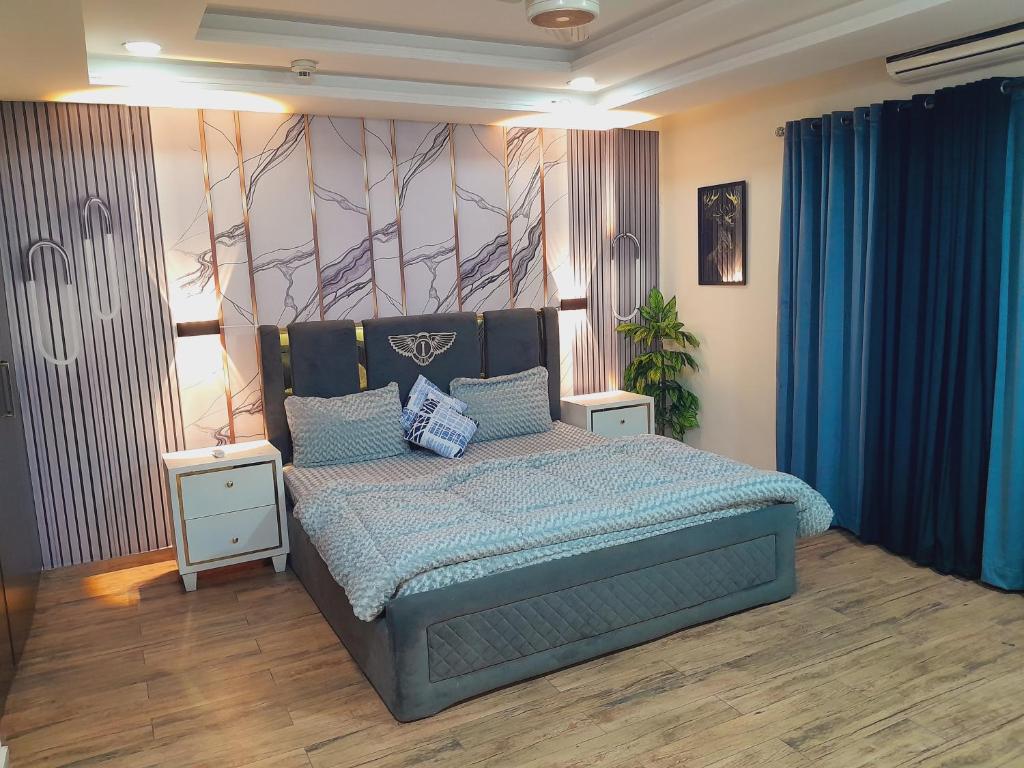 a bedroom with a bed with a blue comforter at Urban Pearl Apartment in Rawalpindi
