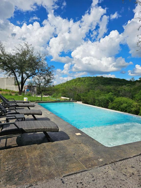 a swimming pool with lounge chairs and a mountain at Quinta La Terquedad in Montemorelos