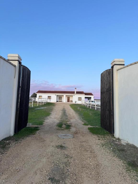 an open gate leading to a white building at Casa Alboroto in Puebla del Río