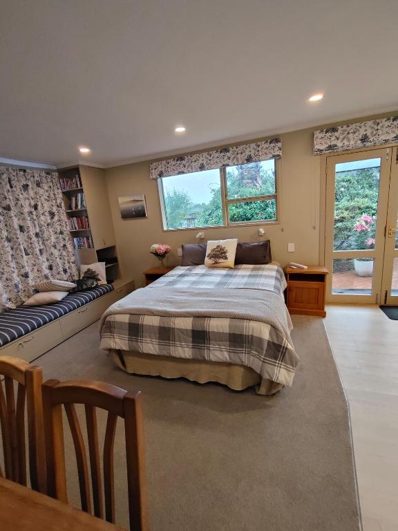 a bedroom with a bed and a couch and two windows at Orchards Retreat in Paraparaumu Beach
