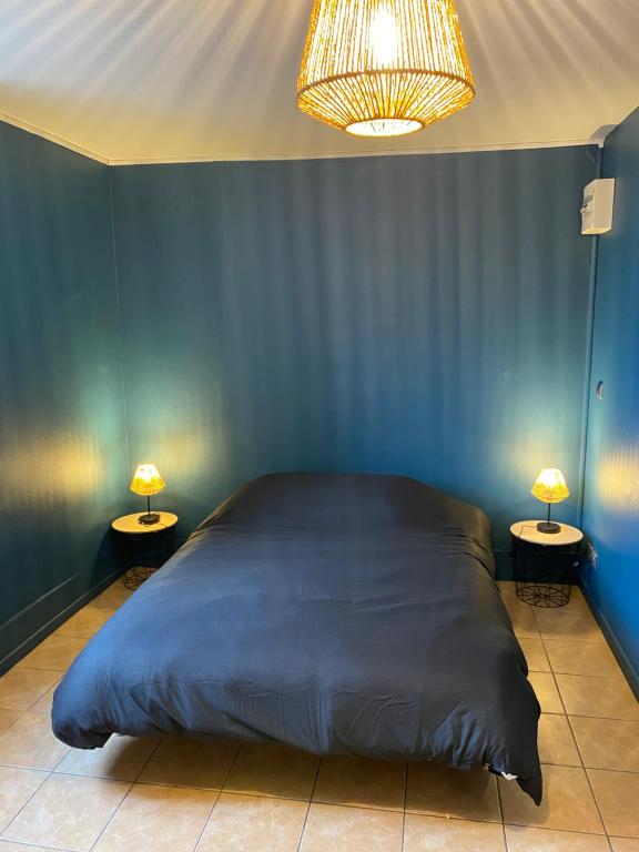 a blue bedroom with a large bed and two lamps at Studio centre ville in Nevers