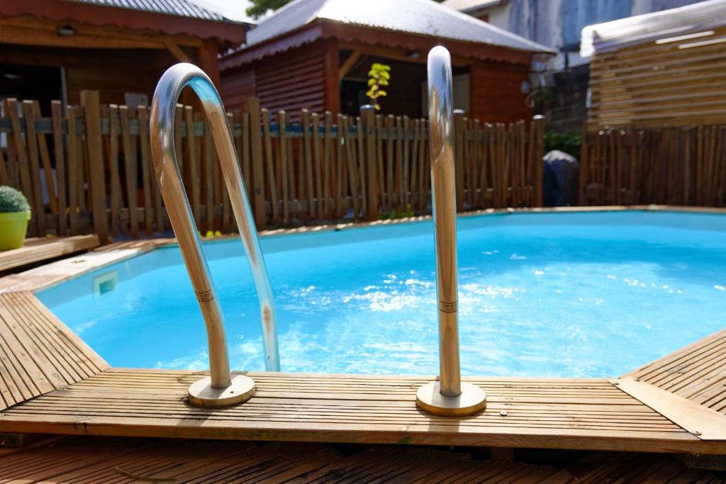 a swimming pool with two metal rails around it at Gwada fun habitation in Saint-Claude