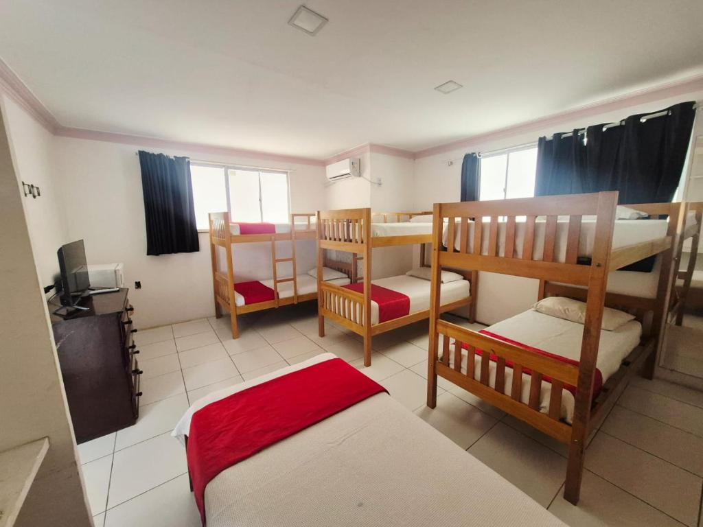 a room with three bunk beds and a television at São Luís Hostel - Dormitórios Compartilhados e Quartos Privativos in São Luís