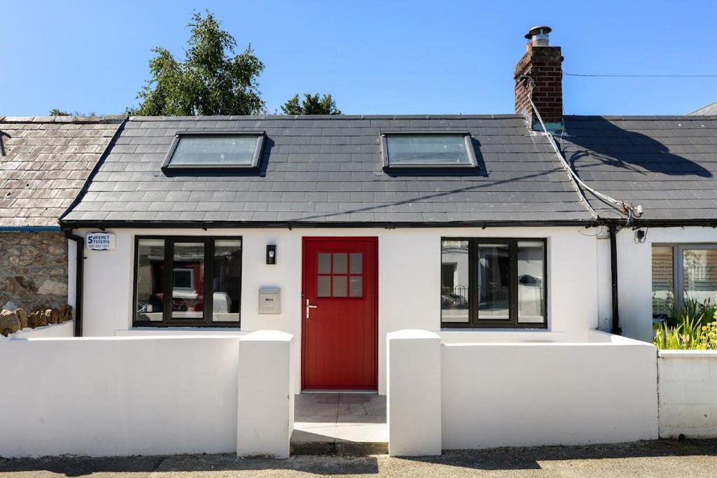 a white house with a red door and windows at Howth Village Cottage in Howth