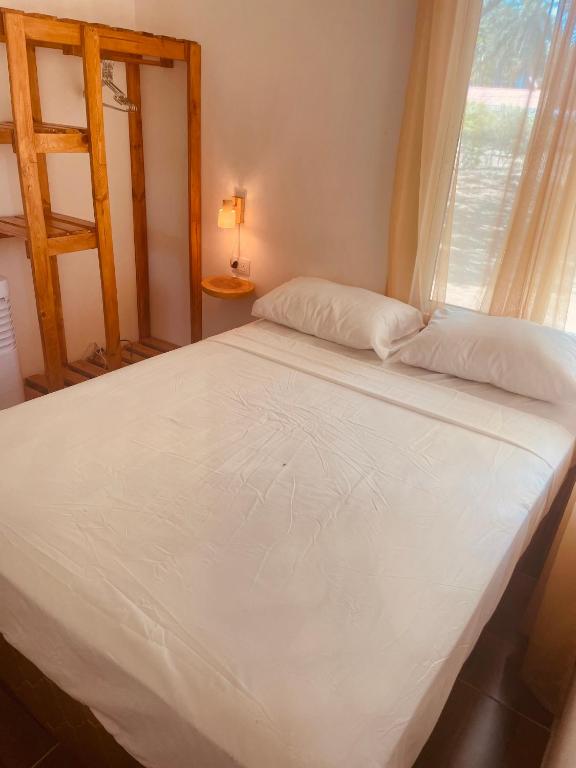 a white bed in a room with a window at Quinta el Refugio in Managua
