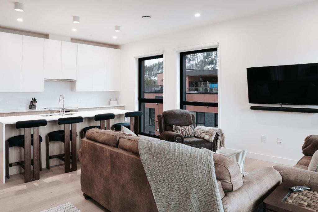 a living room with two couches and a kitchen at Cloudscape Penthouse by Revelstoke Vacations in Revelstoke