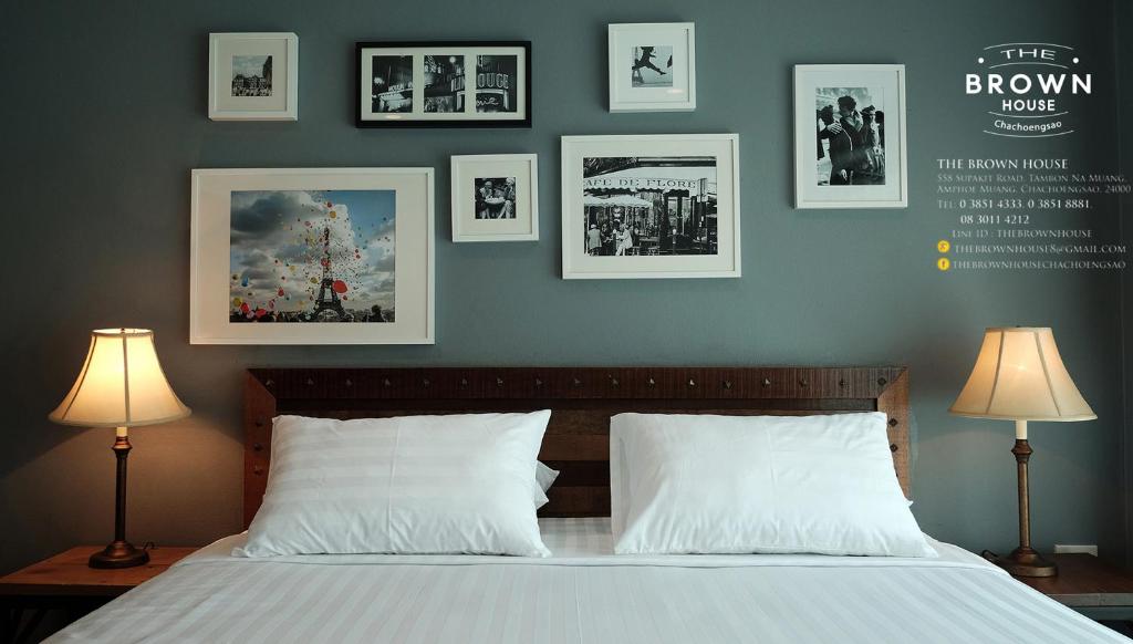 1 dormitorio con 1 cama con cuadros en la pared en The Brown House Hotel en Chachoengsao