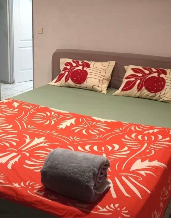a bed with a red and white blanket and pillows at Chez Hinano SIKI in Bora Bora
