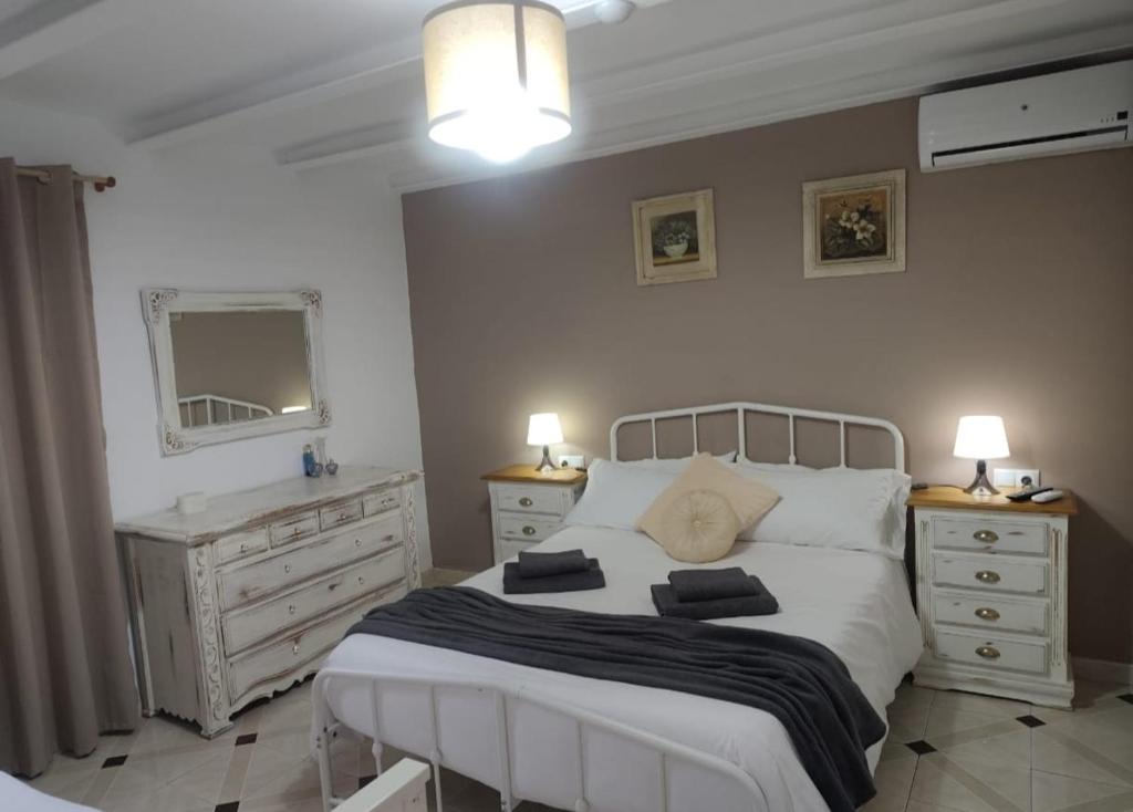 a bedroom with a white bed with two dressers and a mirror at En Poniente in La Línea de la Concepción