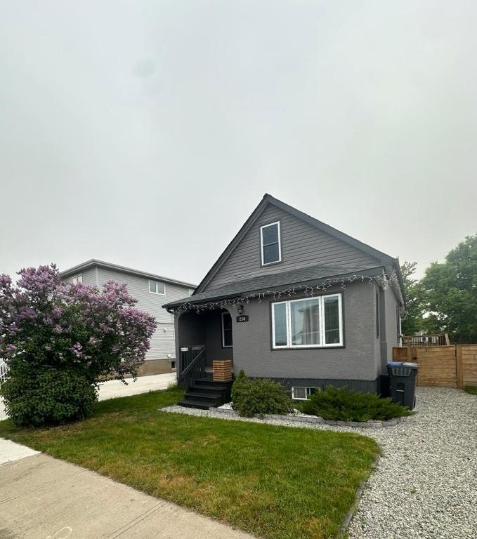 a gray house with a porch and a yard at Friendship Residence in Thunder Bay