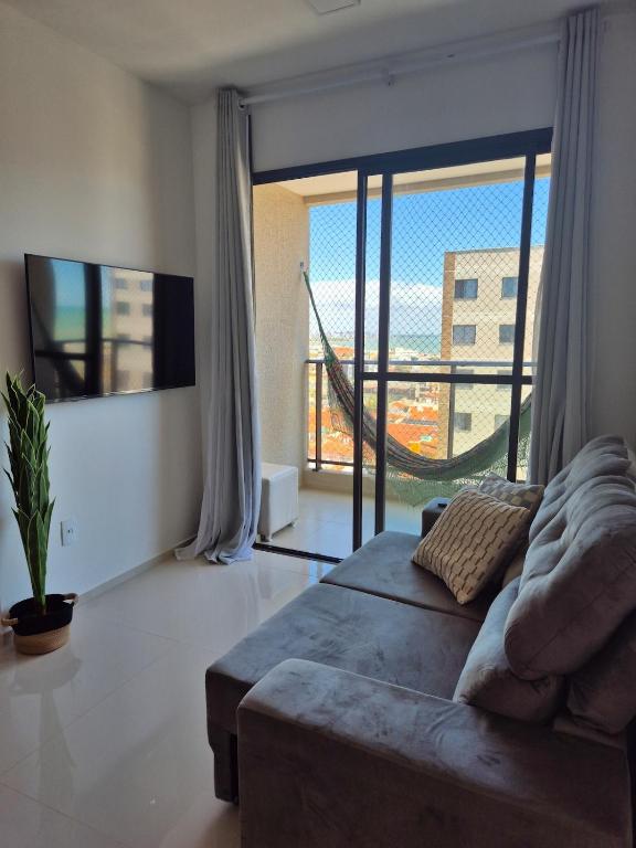a living room with a couch and a large window at Beira Mar Apartment Aracaju in Aracaju